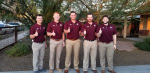 five young men posing with "gig-em" sign