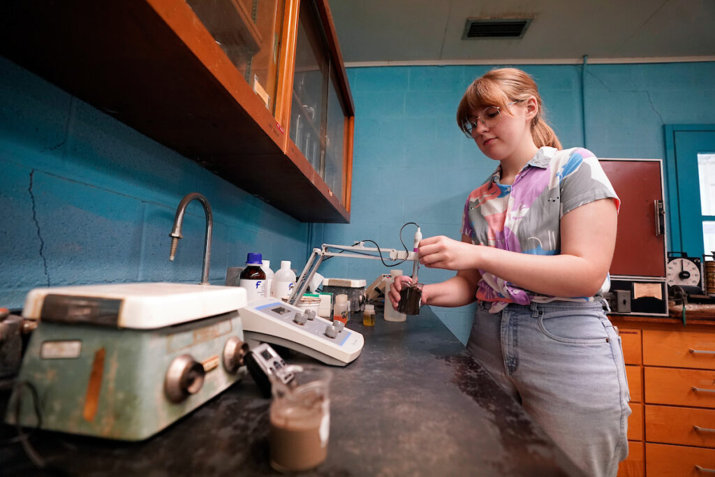 Student analyzing dirt using a device in lab