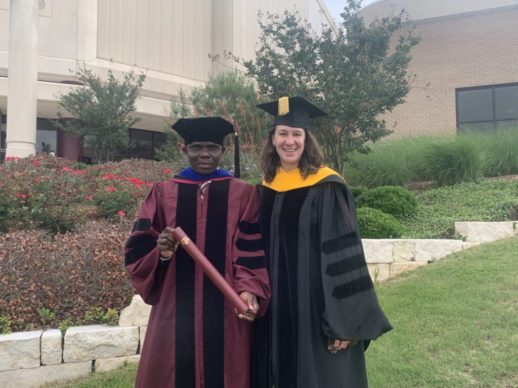 Dr. Perejitei Bekewe '21 and Dr. Jamie Foster standing outdoors in graduation regalia