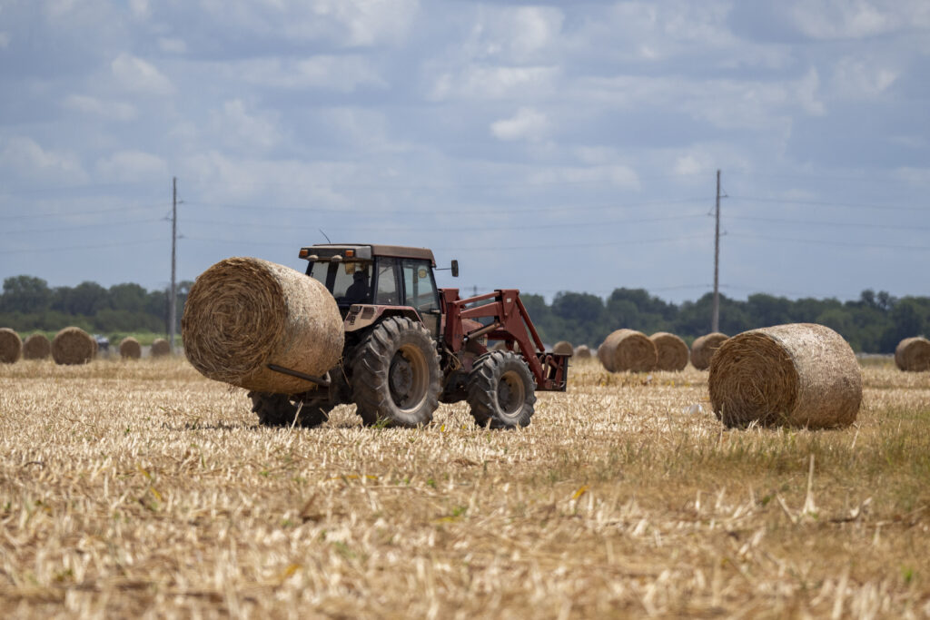 Tractor carrying round bale of hay.