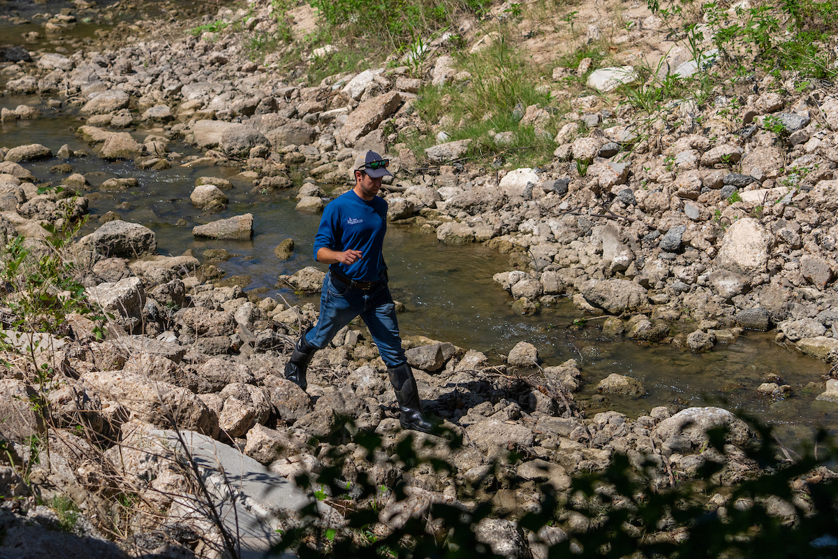Man stepping carefully over rocks along a small stream